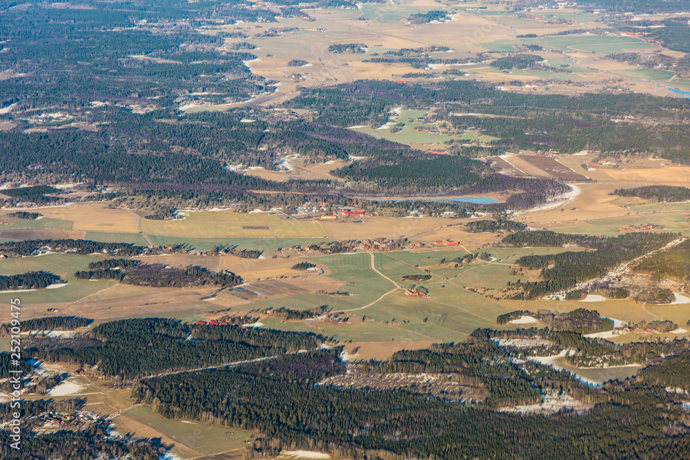 Obraz premium Sweden landscape with forest, field and small settlements north of Stockholm during winter - aerial view 