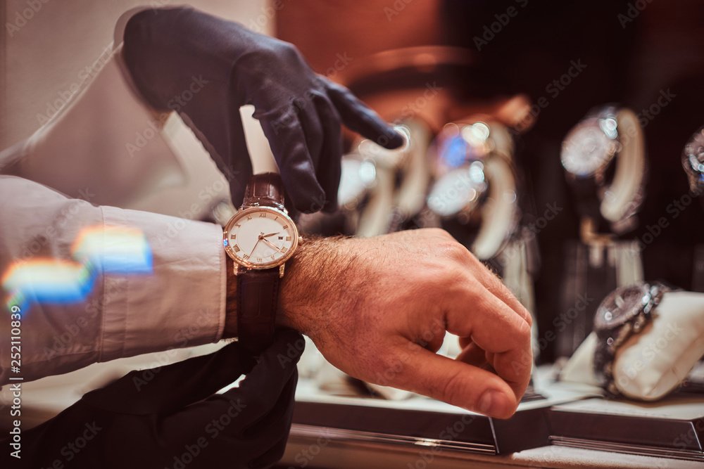 Assistant helps the client to try on exclusive men's watches, close-up hands. Assistant helps the client to try on exclusive men's watches, close-up hands.