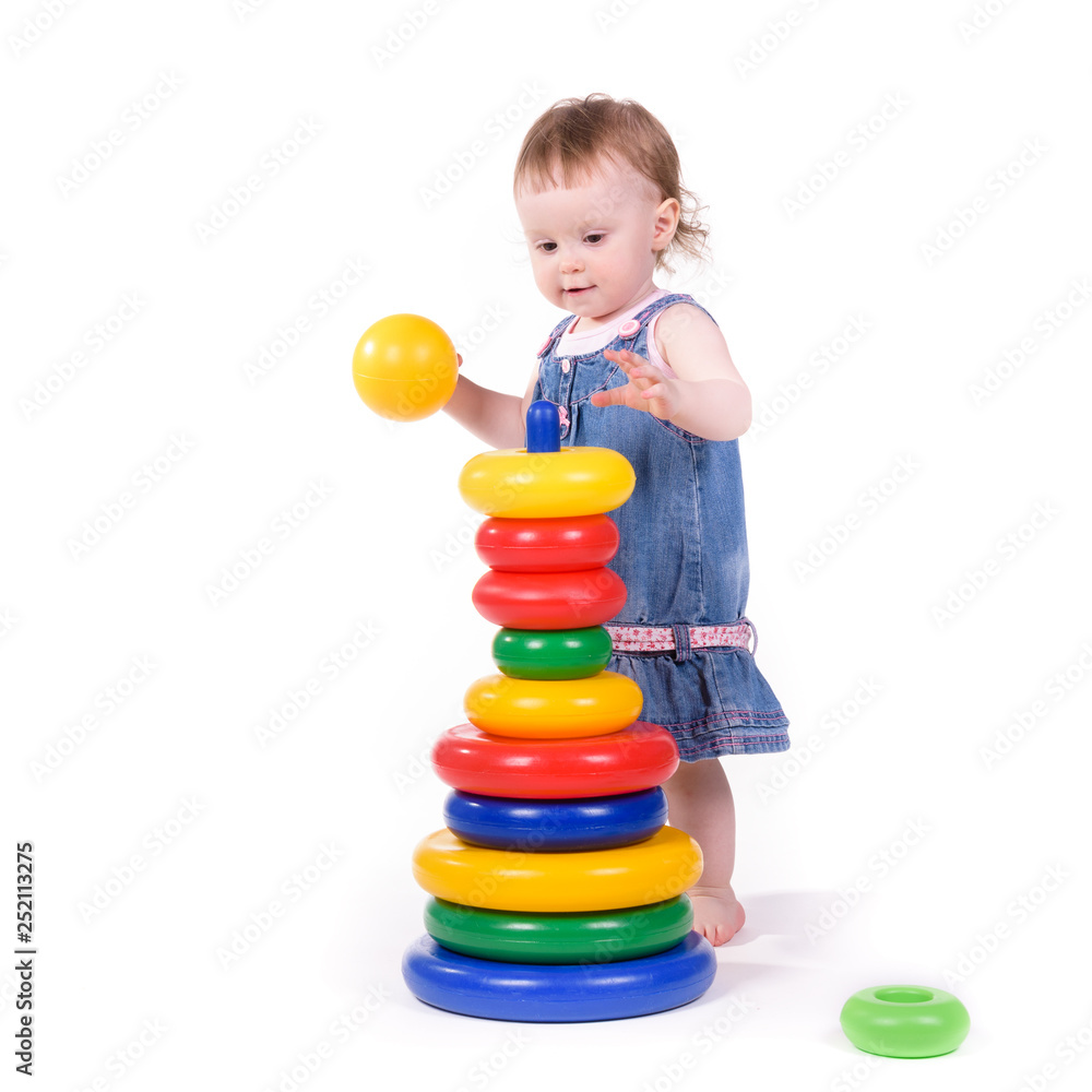 Child collects toys. Small child plays with teaching colored toys. Isolated over white background