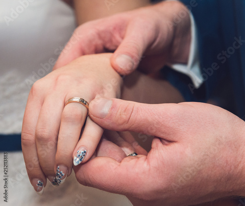Young bride and groom put each other's gold rings on a finger and show them on their hands.