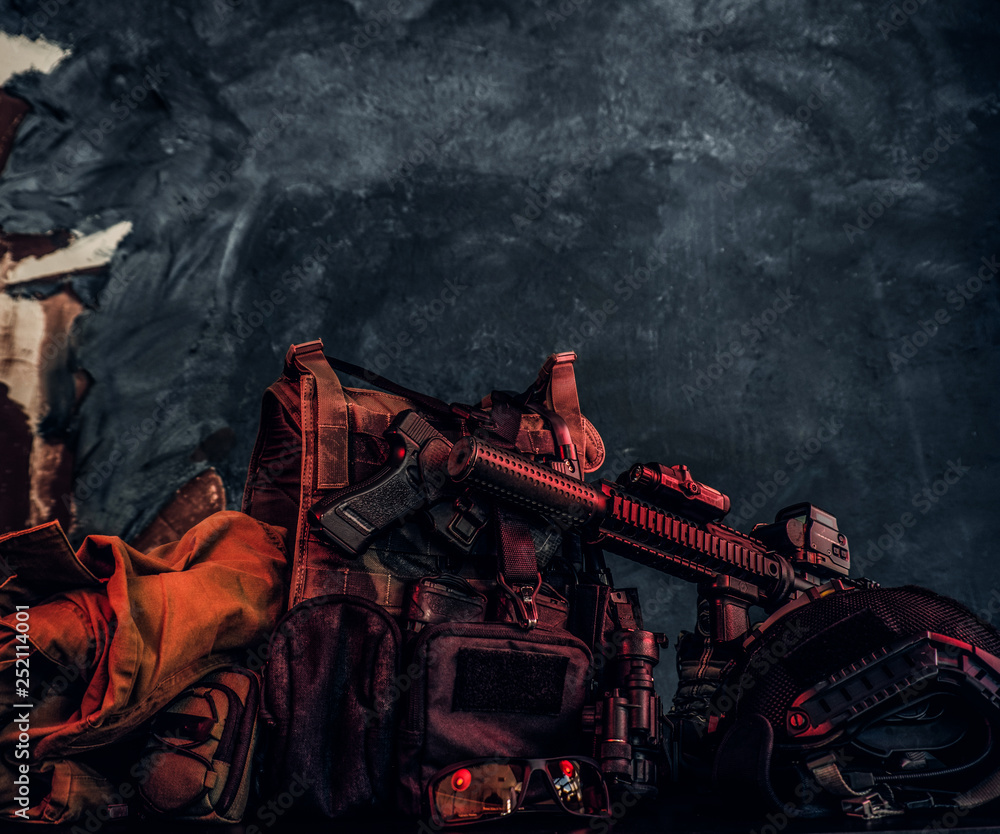 Military uniform and equipment. Body armor, gun, assault rifle, helmet, night vision goggles. Studio photo against a dark textured wall Military uniform and equipment. Body armor, gun, assault rifle, helmet, night vision goggles. Studio photo against a dark textured wall