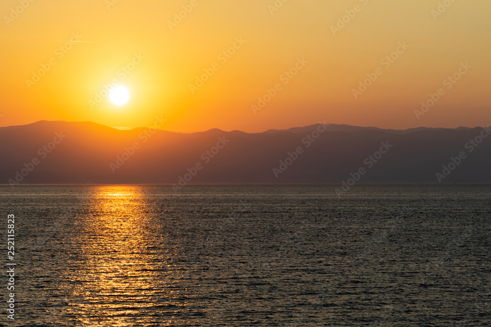 Golden sunrise over the sea. Solar reflections on the water's surface.