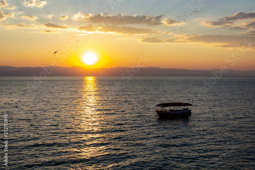 Sunrise over the sea, view of the drifting boat. © PhotoRK