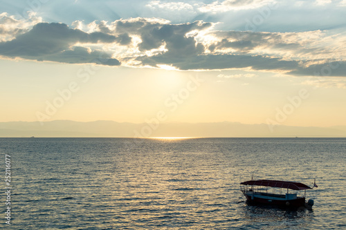 Sunrise over the sea, view of the drifting boat. © PhotoRK