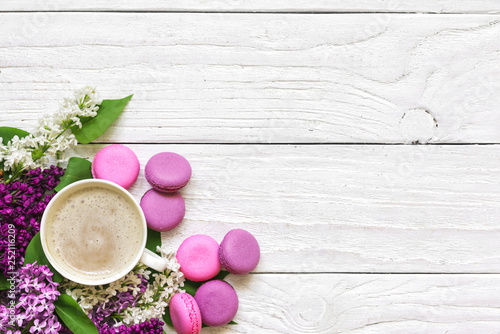 spring lilac flowers bouquet with macarons and cappuccino cup on white wooden table with copy space for your text