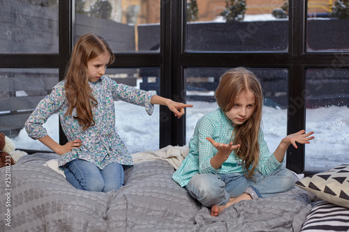 The cute little girl is snitching at her sister, pointing at her with her finger photo