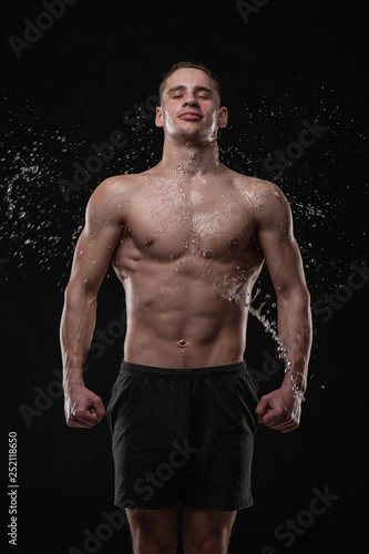 Handsome young man posing with water splashes on face and chest in Studio shot © Vladimir
