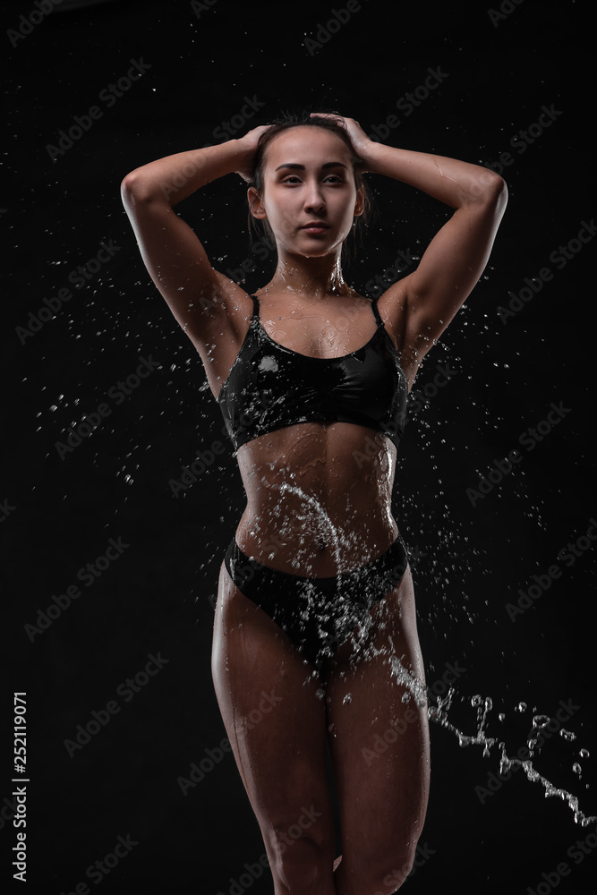 Fototapeta premium Handsome young girl posing with water splashes on face and chest in Studio shot