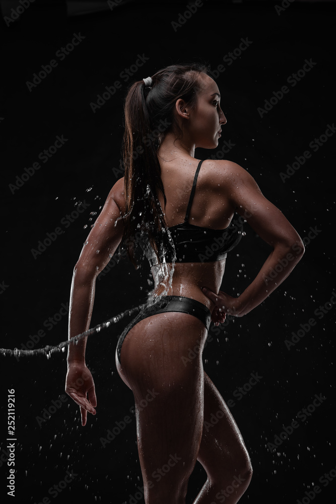 Obraz premium Handsome young girl posing with water splashes on face and chest in Studio shot
