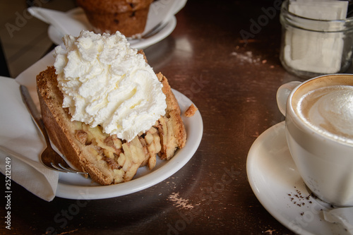 Canvas Print A slice of apple pie with whipped cream and a cappuccino coffee on a wooden table