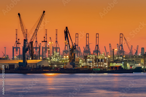 Cranes silhouetted against the evening sky in Hamburg Harbor, Germany, at dusk. The Port of Hamburg (Hamburger Hafen) is a sea port on the river Elbe. It is Germany's largest harbor.