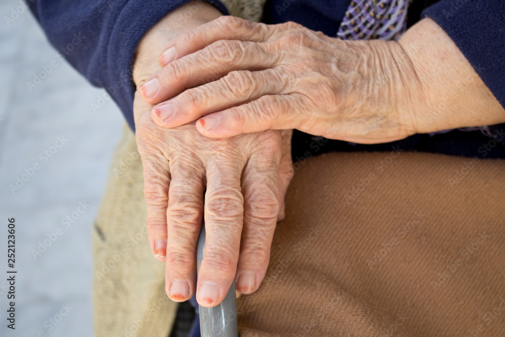 Fototapeta premium Elderly hands on a wheelchair. 