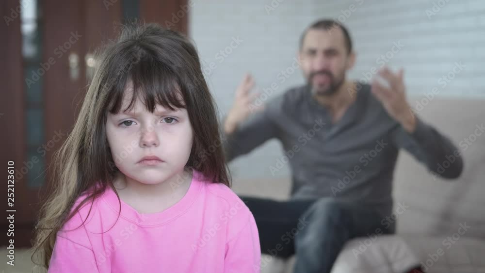 Portrait of a child in depression. The father screams at the sad little daughter. Portrait of a child in depression. The father screams at the sad little daughter.