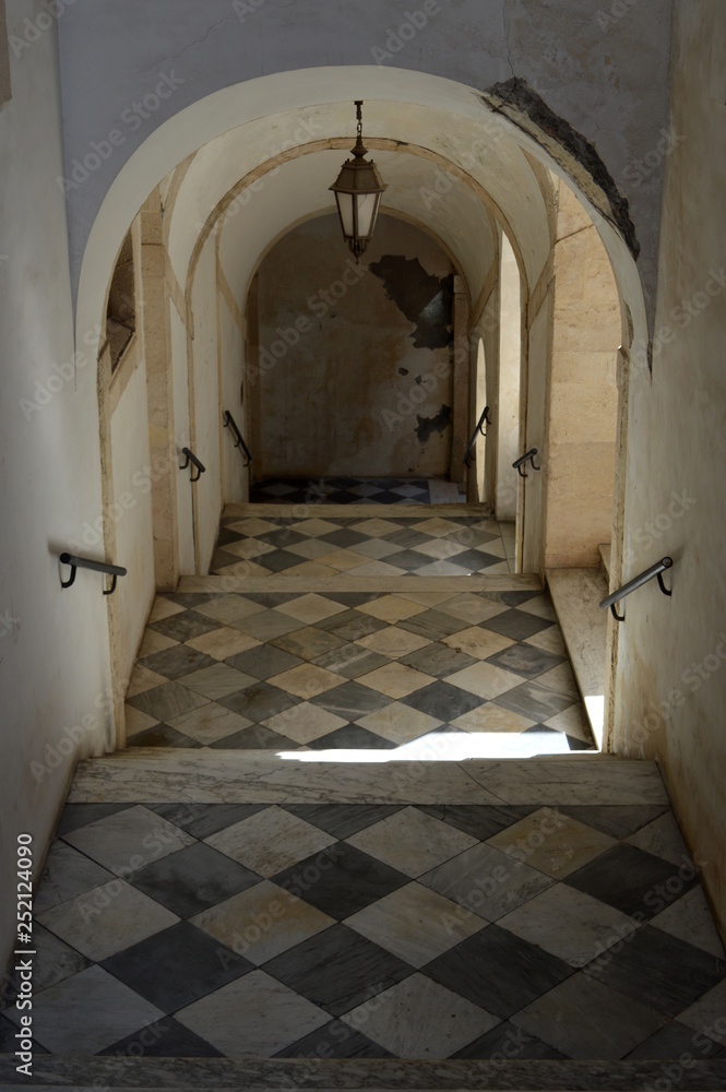 Fototapeta premium Old staircase with arched ceiling and chess tiled floor, Catania, Sicily, Italy