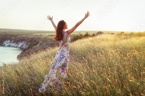 Happy woman in light dress standing in grass 
