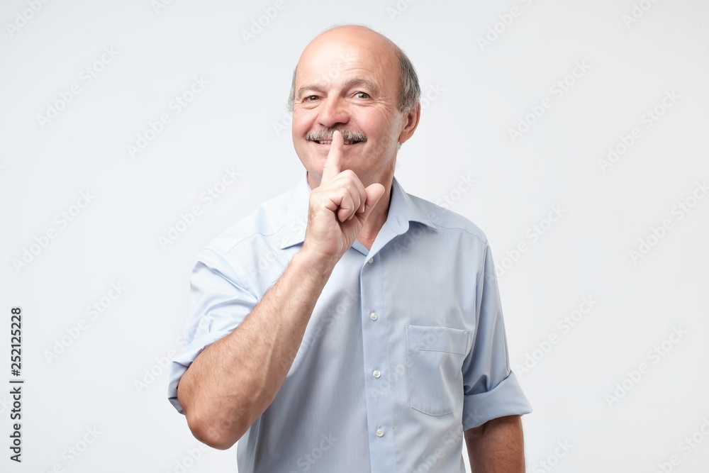 mature man with finger on lips asking for silence. mature man with finger on lips asking for silence.