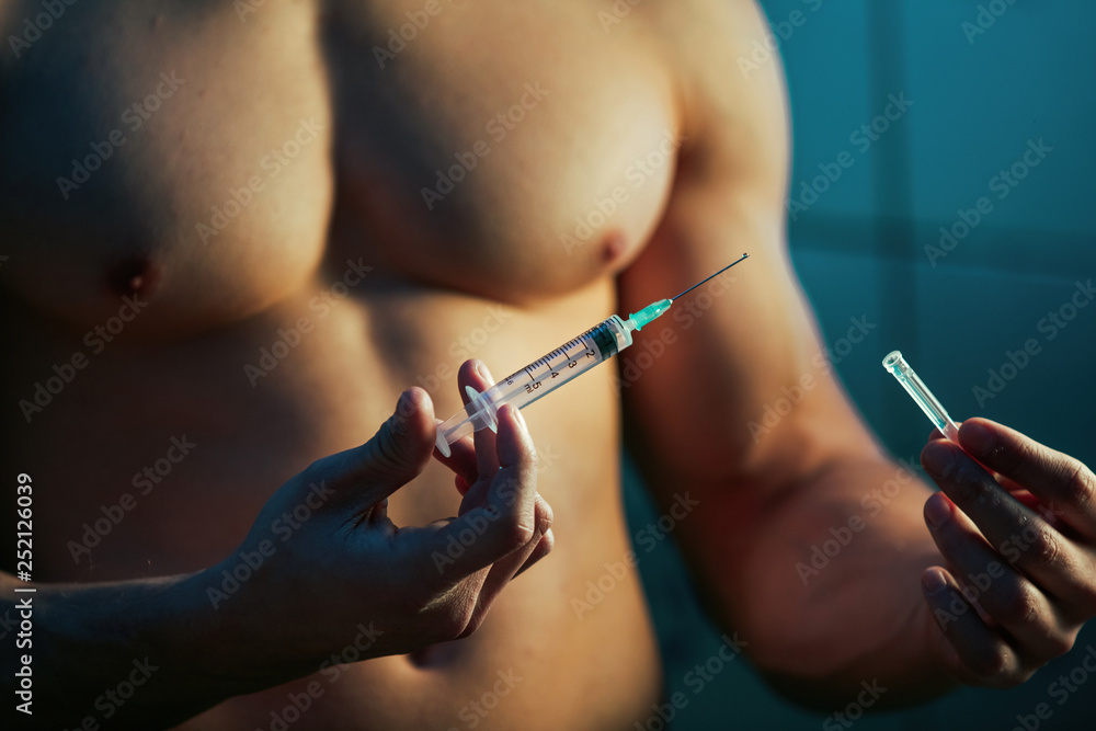 Close up of sportsman using steroids for increasing muscular growth. Close up of sportsman using steroids for increasing muscular growth.