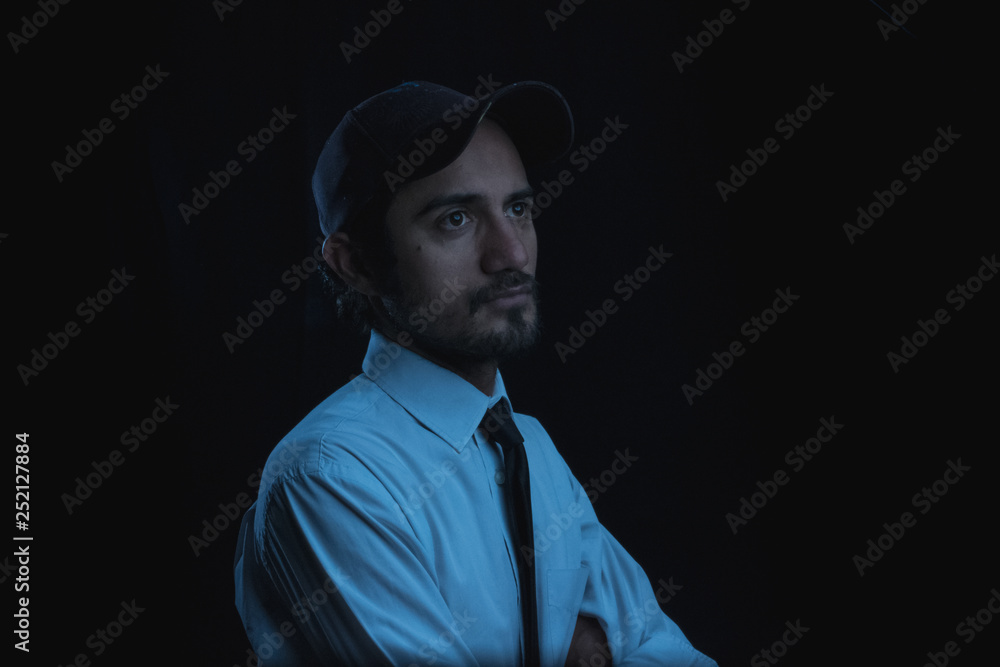 portrait with black background of a young man in cap shirt and tie portrait with black background of a young man in cap shirt and tie
