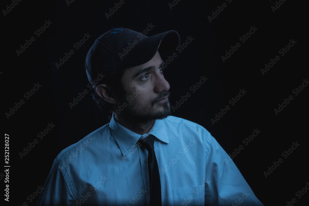 portrait with black background of a young man in cap shirt and tie portrait with black background of a young man in cap shirt and tie