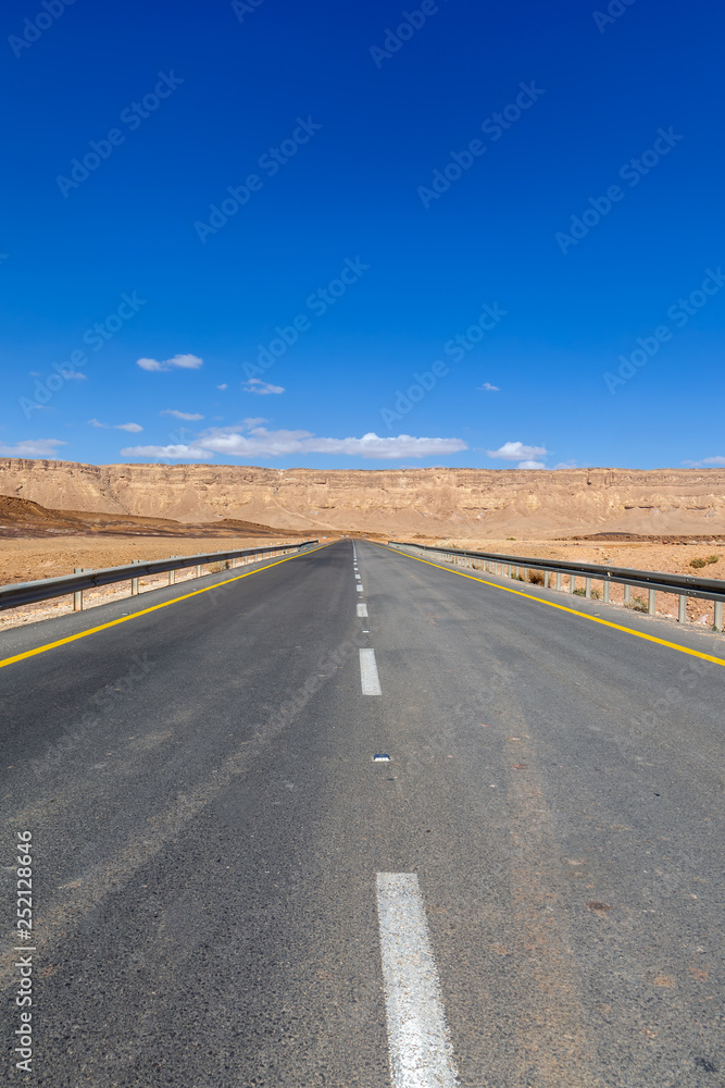 Fototapeta premium Empty highway leading to the mountains through the desert
