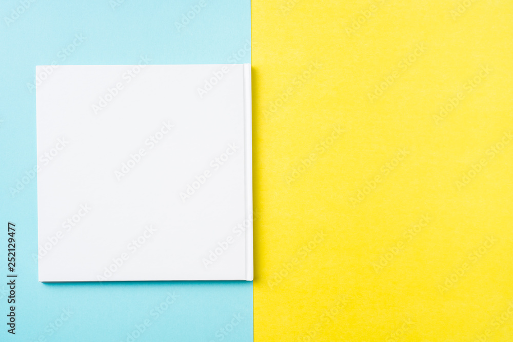 opened white square notebook on yellow and blue