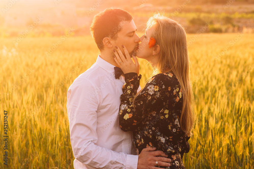 Man and woman with closed eyes embracing and kissing in wheat field on the dusk Man and woman with closed eyes embracing and kissing in wheat field on the dusk