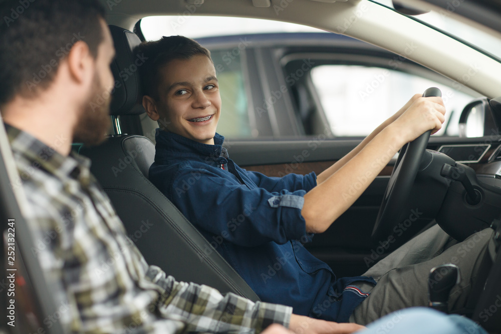 Handsome mature man and his young son buying a new automobile together