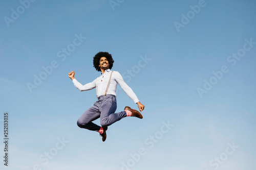 Smiling man jumping in the air against blue sky