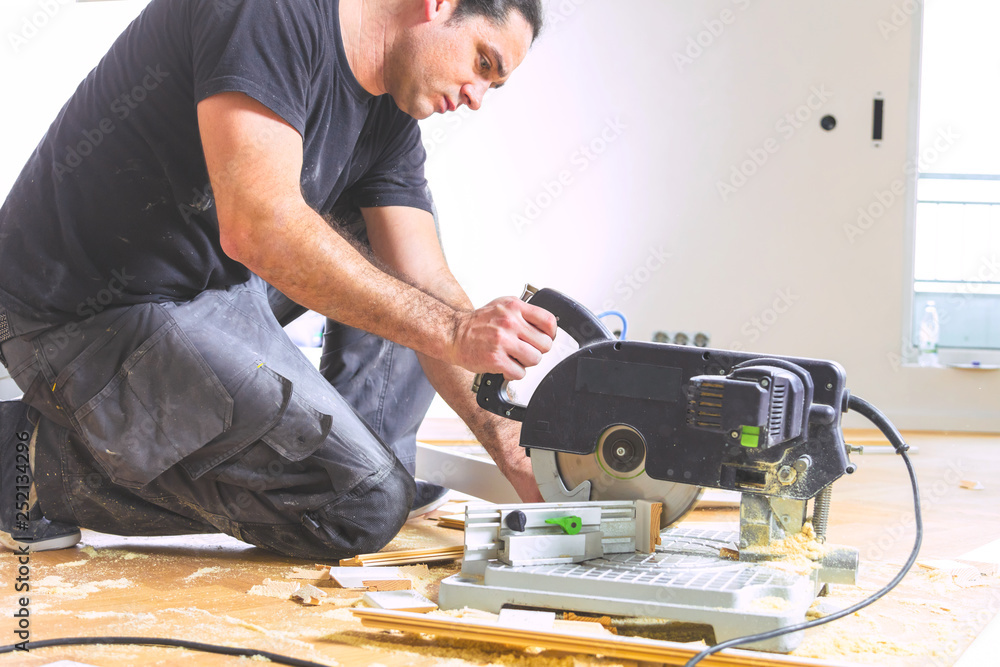 Man with a chop saw cuts skirting boards on a construction site. Lay