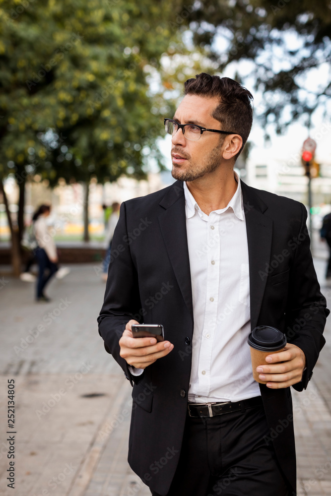 Businessman with takeaway coffee and cell phone in the city on the go Businessman with takeaway coffee and cell phone in the city on the go