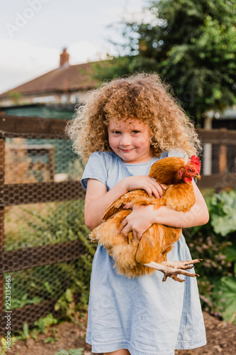 Smiling girl hugging hen photo