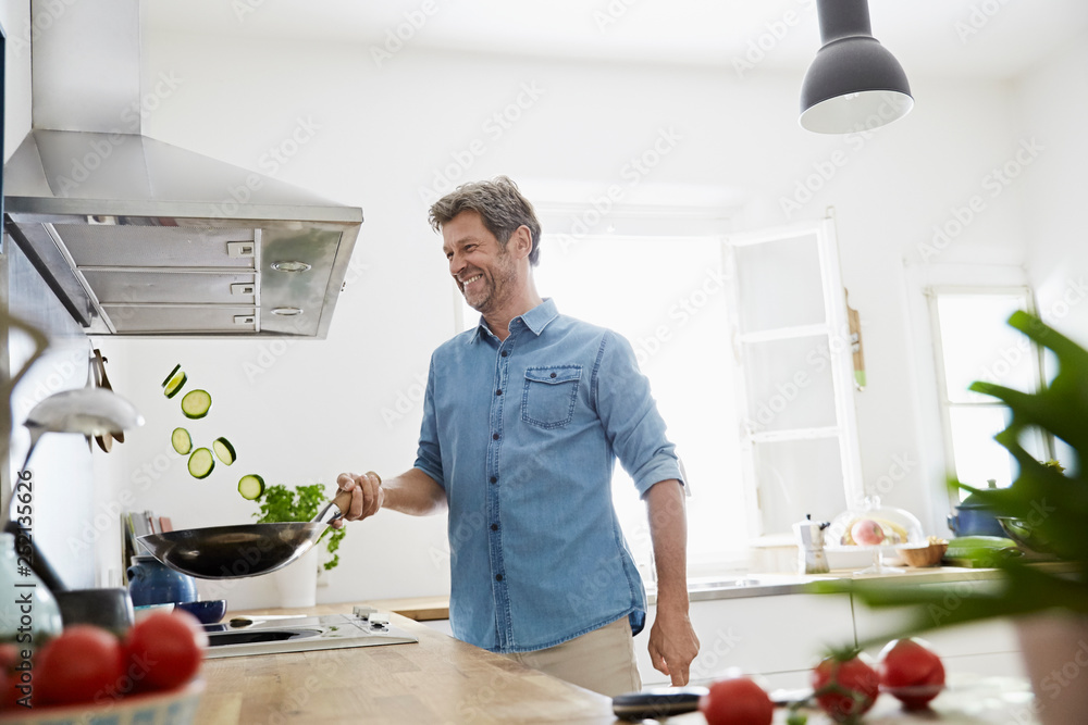 Mature man in his kitchen frying vegetables Mature man in his kitchen frying vegetables
