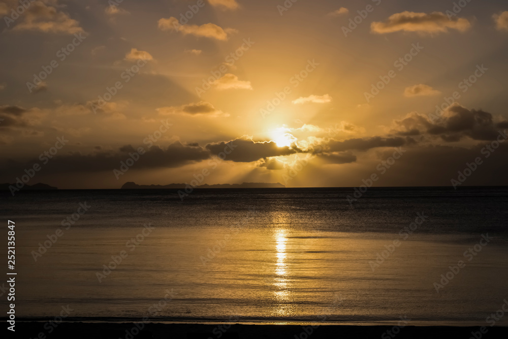 Sunset Rays over Calm Ocean with Rock Islands on Horizon
