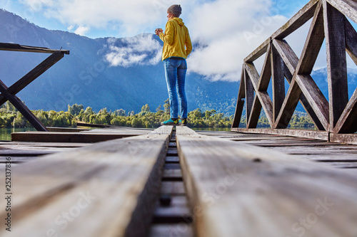 Chile, Chaiten, Lago Rosselot, woman standing on jetty holding mug photo