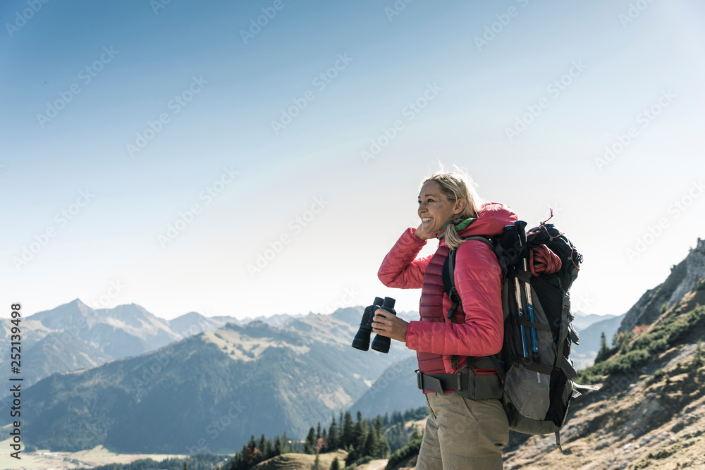 Austria, Tyrol, smiling woman with binoculars on a hiking trip Austria, Tyrol, smiling woman with binoculars on a hiking trip
