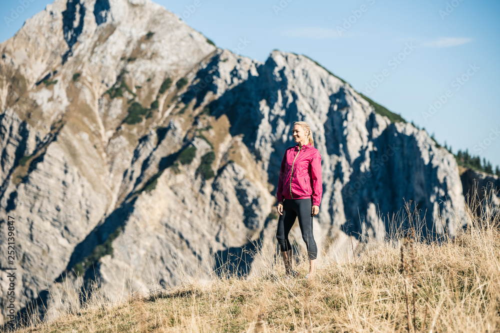 Austria, Tyrol, smiling female athlete standing on alpine meadow