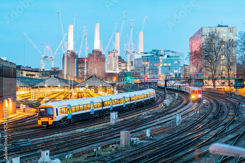 United Kingdom, England, London, view of rail tracks and trains in the evening, former Battersea Power Station and cranes in the background photo