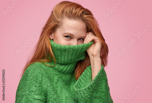 Adorable flirty girl hiding face in sweater 