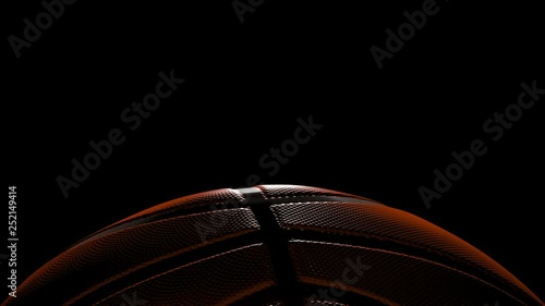 basketball with back lighting slowly spins at bottom of frame over black - 3d.