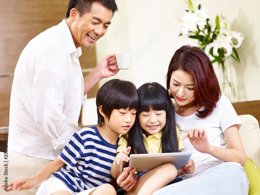asian family with two children using digital tablet together asian family with two children using digital tablet together