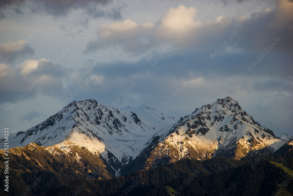 Landscape, snowy mountains and cloudy sky above