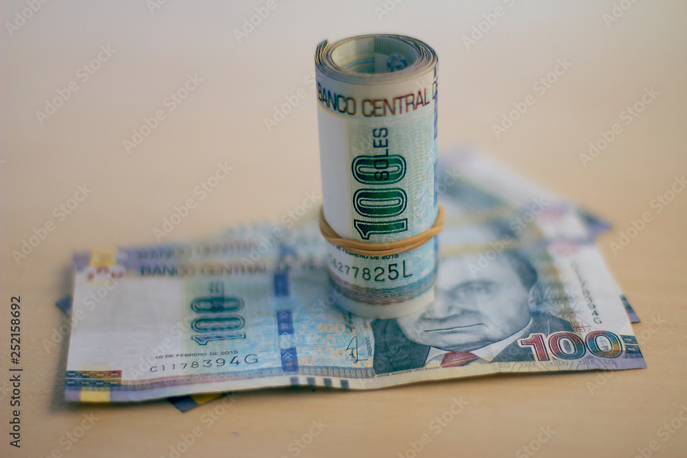 Peruvian currency soles bills rolled with rubber on a wooden table Peruvian currency soles bills rolled with rubber on a wooden table