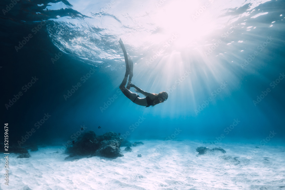 Woman freediver dive over sandy sea with fins. Freediving in blue ocean - obrazy, fototapety, plakaty 