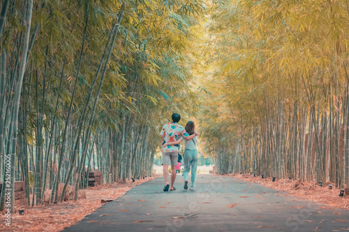 Back view of happiness Male and female couples walking hand in hand and fall in love along the bamboo park in the evening