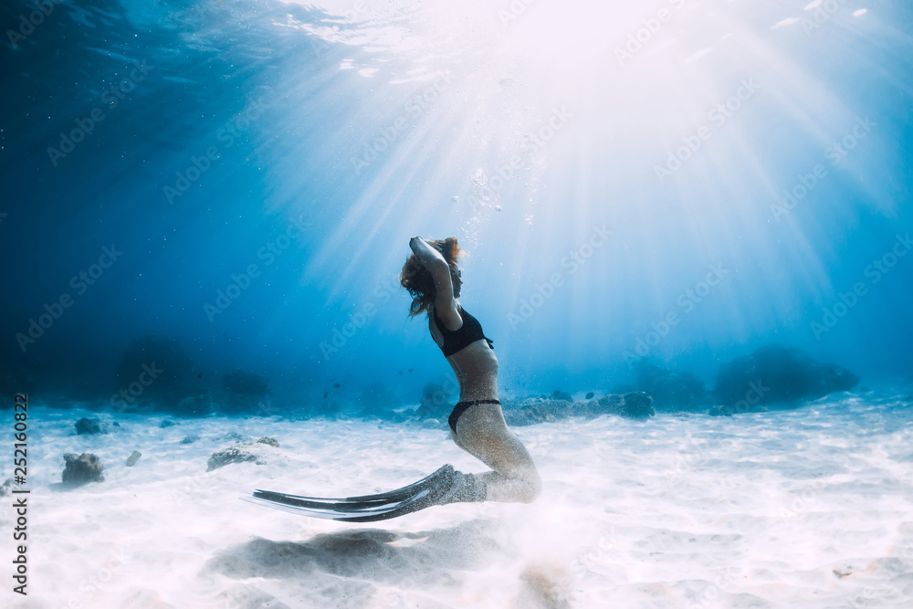 Woman freediver with pose over sandy sea with fins. Freediving underwater in Hawaii
