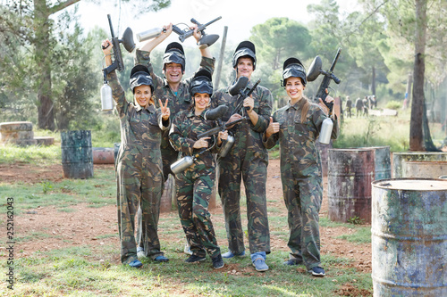 Portrait of happy team of paintball players with marker guns outdoors