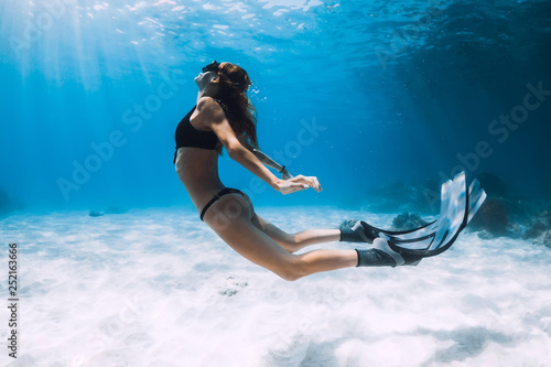 Woman freediver swim over sandy sea with fins. Freediving underwater in blue ocean