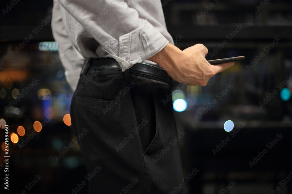 businessman checking on mobile phone in a modern office with out of focus lights in the background. office worker night at the office. modern businessman concepts.
