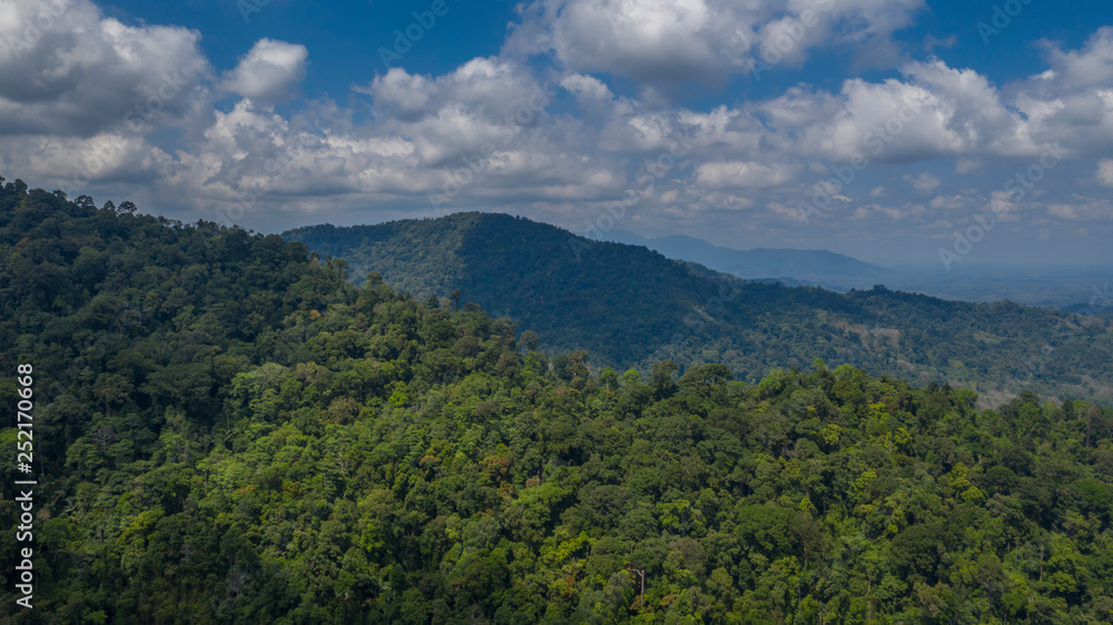 Green slopes of the Southern Thai hills with mountainous perspective and cloudy blue sky