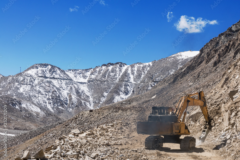 Hydraulic breaker divide a rock for roadway construction on mountain Hydraulic breaker divide a rock for roadway construction on mountain